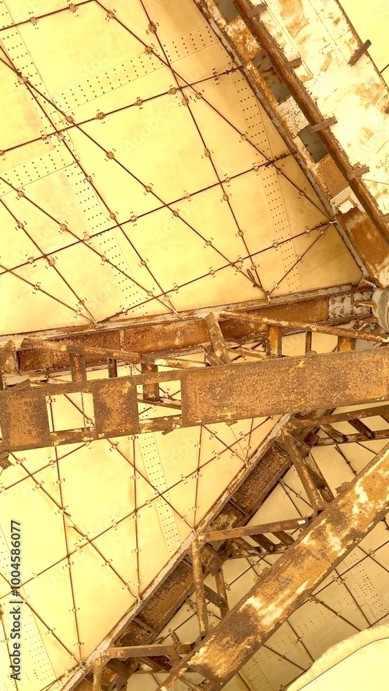 Rusted beams intersect beige panels forming geometric ceiling structure ...
