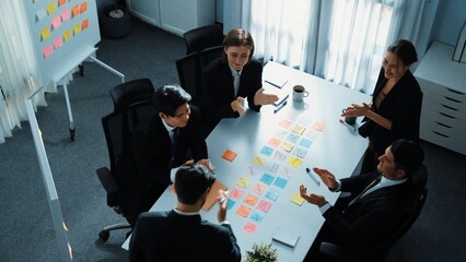 Top view of business people brainstorm idea by using sticky notes while planning marketing strategy at meeting room. Group of diverse team discuss about financial plan. Teamwork concept. Directorate.