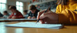 © Jirut - a student taking an educational admission test in a university classroom. close-up of the student's hand as they write answers on the test paper