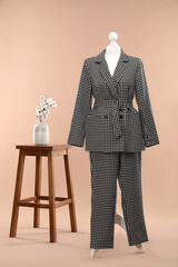 Wall Mural - Female mannequin with suit, stool and cotton flowers on beige background