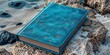 © Artur Lipiński - Weathered blue book resting on rocks by the sea, vintage travel and adventure concept