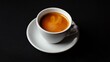 © Rstm - A cup of espresso with crema on top in a white cup and saucer against a black background.