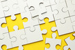 © New Africa - White puzzle pieces on yellow background, top view