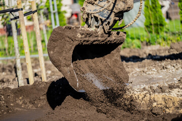 Muddy and dirty excavator digging ground and soil for coming construction project of building new houses