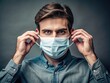 © Man888 - Individual putting on a mask to prevent the spread of germs and promote health safety practices