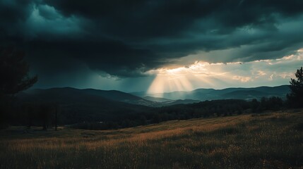 Wall Mural - A field with mountains and a sky with sunbeams breaking through the clouds.