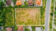 © fotofabrika - Aerial view of an empty plot of land surrounded by residential houses on a sunny day