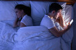 © Prostock-studio - Cheating Boyfriend. Man Texting On Phone Lying Near Jealous Girlfriend In Bed At Night. Top View, Low Light