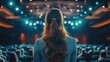 © SY - A businesswoman stands on stage, facing an audience. The photo shows her in a speaking position, ready to deliver a presentation.
