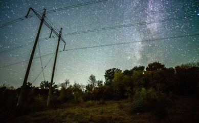 Wall Mural - Space with galaxy . Milky way on the blue sky .Dark and cold night at summer . Trees on the backgound with stars . Power lines in the night , powerstation and galaxy