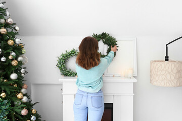 Wall Mural - Woman decorating festive living room with Christmas wreathes