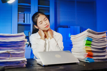 confident Asian businesswoman works late into the night, surrounded by a stack of papers in a busy office. Overtime leads to office syndrome symptoms like neck pain, headaches, and chronic stress.