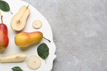 Board with ripe pears on grey background