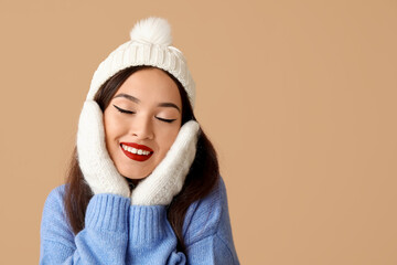 Sticker - Beautiful young Asian woman in warm clothes on brown background