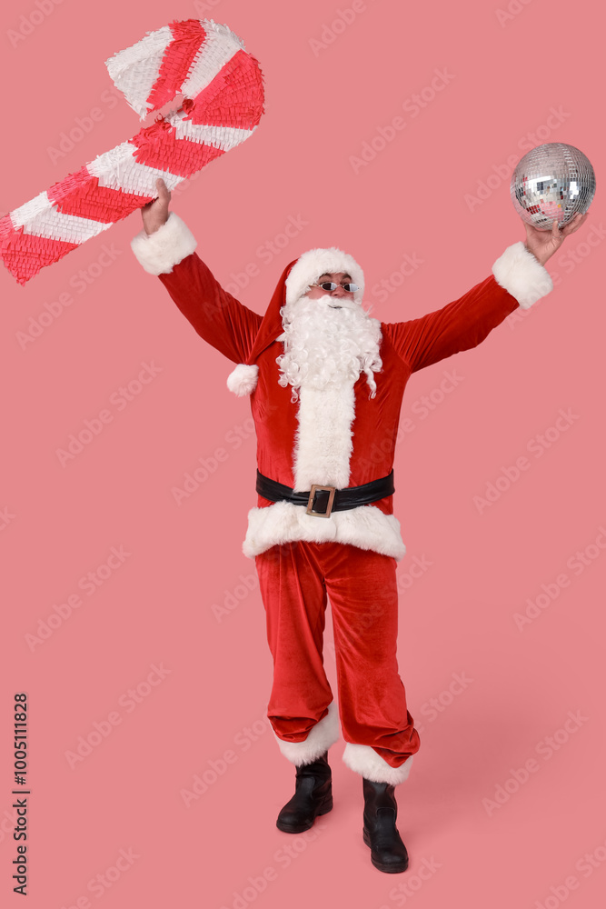 Cool Santa Claus with disco ball and candy cane pinata on pink background