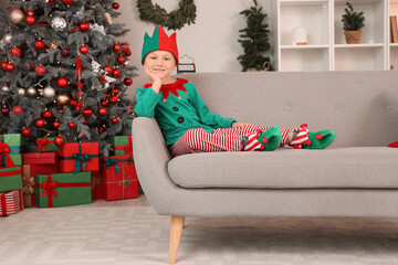 Wall Mural - Cute little boy in elf costume sitting at home on Christmas eve