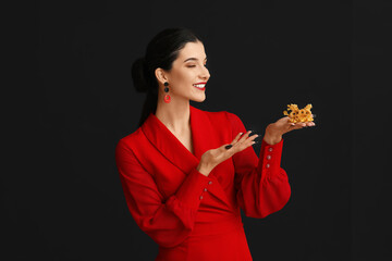 Poster - Beautiful young happy woman pointing at golden dragon figurine on black background. Chinese New Year celebration