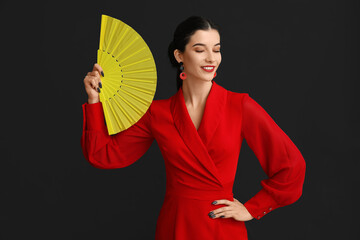 Wall Mural - Beautiful young happy woman with fan on black background. Chinese New Year celebration