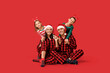 © Pixel-Shot - Happy family in Christmas pajamas on red background