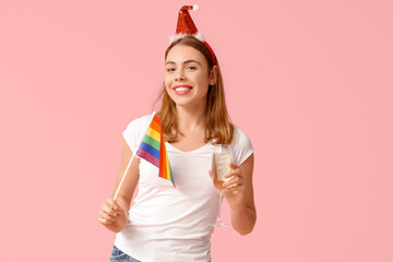 Poster - Young woman in Santa hat with LGBT flag and glass of champagne on pink background