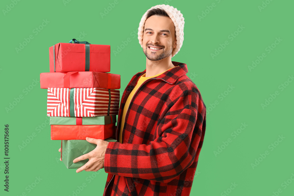 Handsome man with Christmas presents on green background