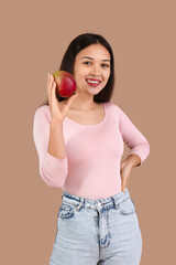 Wall Mural - Beautiful young Asian woman with fresh mango on brown background