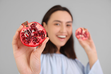 Poster - Beautiful young woman with fresh pomegranate on grey background