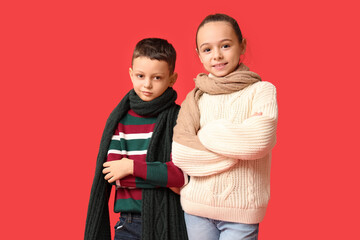 Poster - Cute little happy children in warm winter clothes on red background