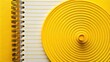 © kittipon - Vibrant yellow spiral design sits atop a ruled notepad background, featuring horizontal lines, creating a striking visual contrast and a sense of creative playfulness.