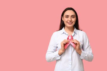 Canvas Print - Pretty young woman with pink ribbon on color background. Breast cancer awareness concept