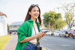 © sitthiphong - Cheerful beautiful Asian woman holding smartphone and camera with looking for tourist attractions.