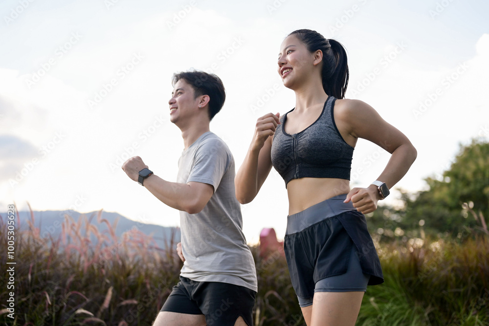 An active, sporty Asian couple in sportswear is enjoying a run together ...