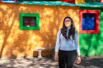 Young Latina woman smiling in front of the vibrant, colorful houses of Caminito, located in the La Boca neighborhood of Buenos Aires.