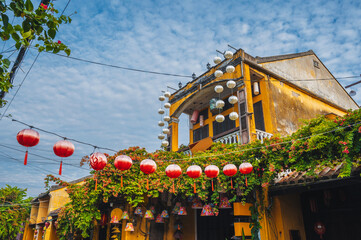 facade of an ancient Asian yellow house decorated with red Chinese lanterns for a holiday in the old town in Hoi An in Vietnam