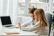 © SHOTPRIME STUDIO - Happy children studying and playing online at home using laptop, headphones, and phone The boy and girl are sitting at a table in the living room, fully engaged in their elearning activities