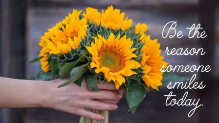 Close-up of a hand gently holding a vibrant bouquet of sunflowers, featuring the quote