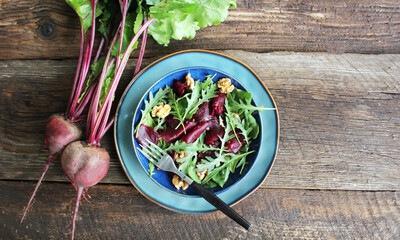 Healthy Beet Salad with fresh sweet baby spinach, arugula, nuts on wooden background . Top view