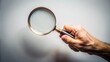 © onehourhappiness - Hand Holding a Magnifying Glass Against a Light Background: Symbolizing Exploration and Discovery