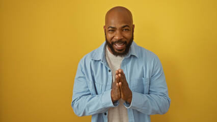 Handsome young african american man with a beard smiling against an isolated yellow background