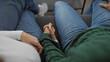 © Krakenimages.com - Close-up of a man and woman holding hands in a cozy living room, symbolizing love and togetherness.