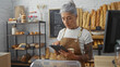 © Krakenimages.com - Mature woman with grey hair working in a bakery shop using a tablet in a modern indoor setting with bread and pastries in the background