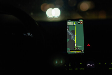 Aufkleber - Driving at night, a smartphone displays navigation directions while the dashboard lights softly illuminate the car interior