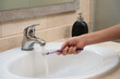© EDUARDOIVAN - toothbrush in the sink held by an unrecognizable hand