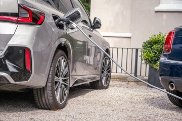 Electric car being charged outside at home in typical British suburban residential setting