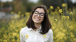 © RedPeaStudio - Joyful Smiling Woman Wearing Glasses Surrounded by Yellow Flowers in Sunny Field