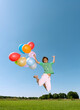 © Westend61 - Boy jumping with balloons outdoors on a sunny day.