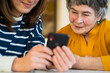 © Zhanna - Girl helps her grandmother with mobile phone.