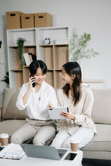 Two Asian businesswoman discuss investment project working and planning strategy with tablet laptop computer on sofa