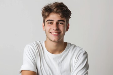 Canvas Print - Young male model with a charming smile and crossed arms against a pure white backdrop , background blur