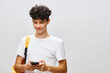 © SHOTPRIME STUDIO - Young man using smartphone, smiling, casual clothing, white background, modern lifestyle, communication, technology, youth engagement, social media interaction, happiness on a neutral backdrop